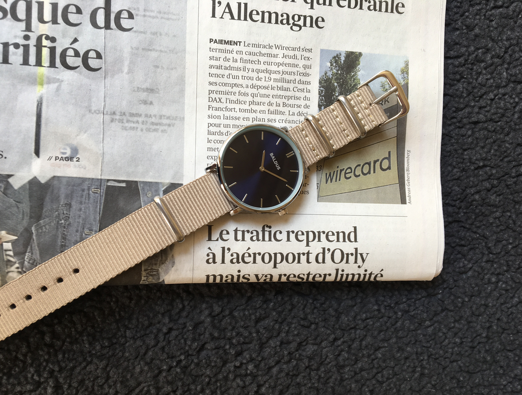 Montre parisienne avec un journal écrit en français derrière.